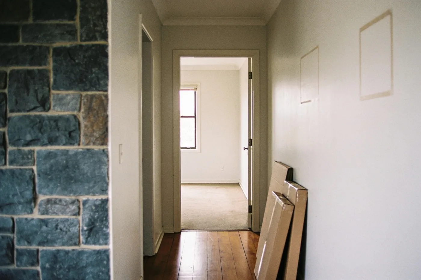 The empty hallway of a suburban family home with flattened moving boxes against the wall